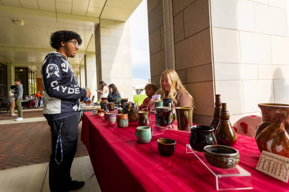 Student looking at pottery display during Student Small Business Market.